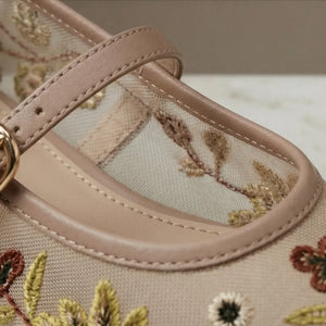 Close-up of a sandal with floral embroidery and a beige strap.