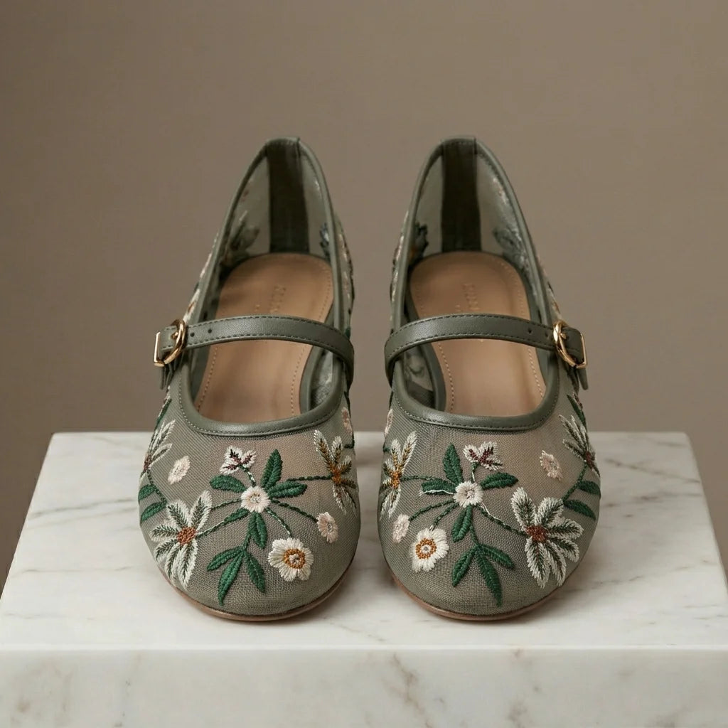 Pair of floral embroidered shoes on a marble surface with a neutral background