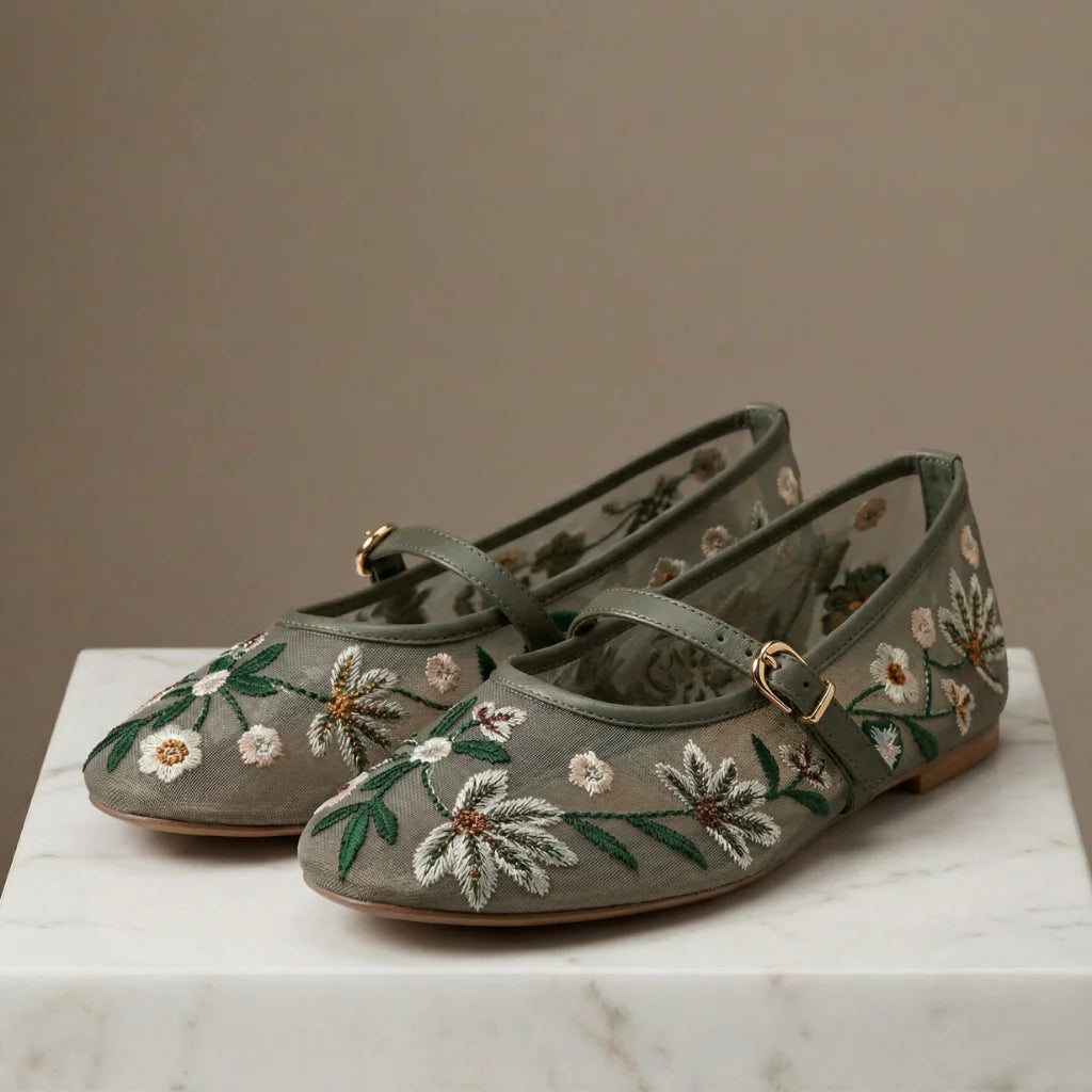 Pair of green embroidered shoes on a marble surface with a neutral background