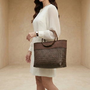 Woman holding a brown woven handbag against a beige background