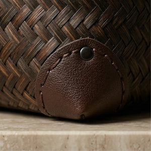 Close-up of a brown woven basket with a leather tag on a wooden surface.