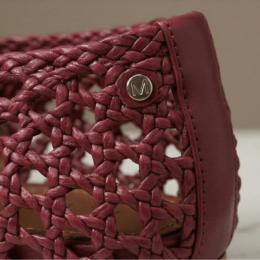 Close-up of a red woven handbag with a brand logo on a neutral background