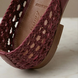 Close-up of a maroon sandal with wooden sole on a light background