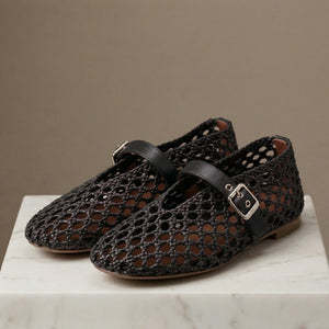 Pair of black perforated shoes with buckles on a marble surface and brown background