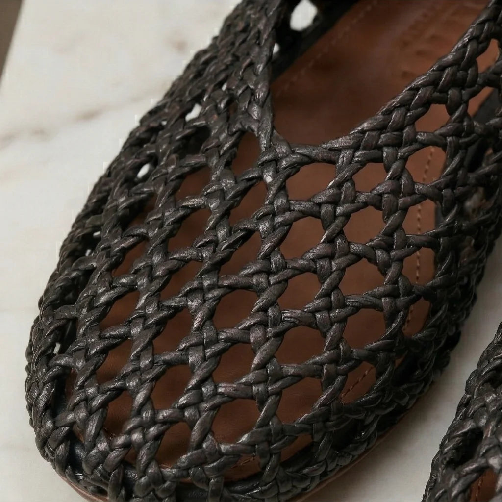 Woven black flat shoes on a light background