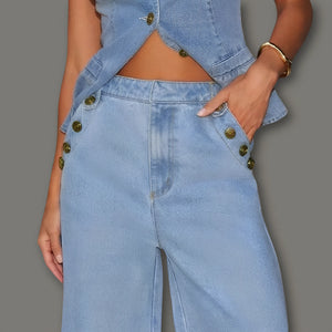 Person wearing a light blue denim outfit with gold buttons on a gray background