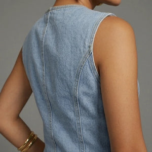 Denim sleeveless top worn by a person on a gray background