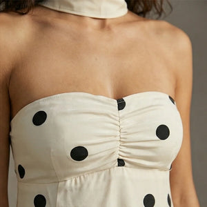 White strapless dress with black polka dots on a neutral background