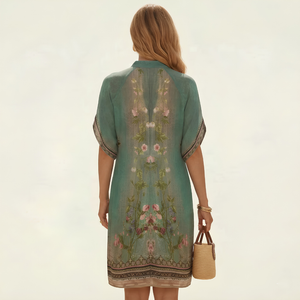 Woman wearing a green embroidered dress holding a straw bag on a light beige background