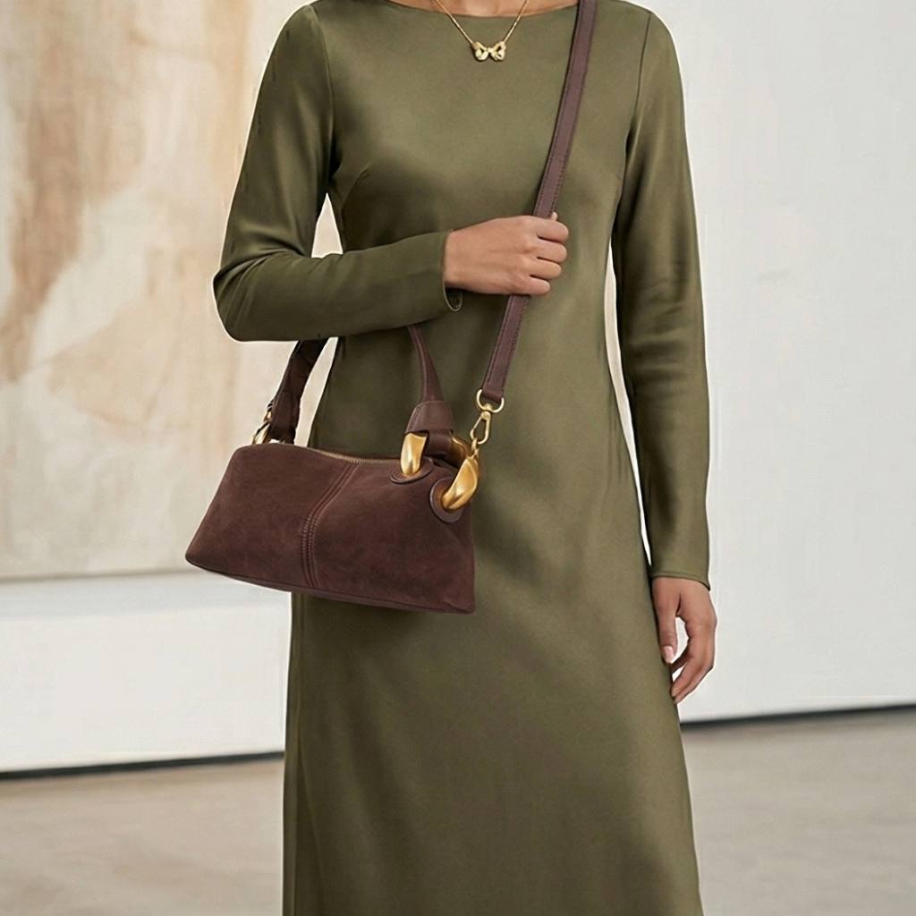 Person wearing an olive green dress holding a brown handbag with gold accents.