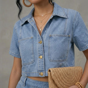 Person wearing a denim shirt and holding a woven clutch against a neutral background