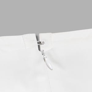 Close-up of a white garment with a silver zipper on a gray background