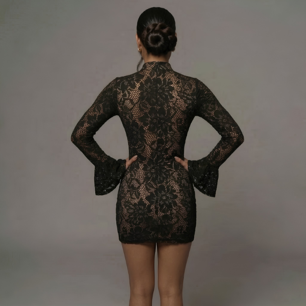 Person wearing a black lace dress against a gray background