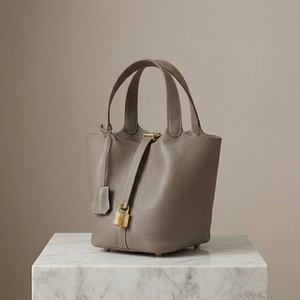 Gray handbag with gold accents on a marble surface against a beige background