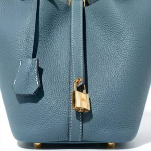 Blue leather handbag with a gold lock on a white background