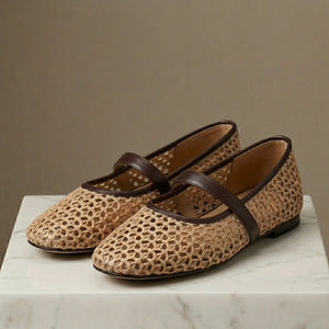Pair of woven shoes with brown straps on a marble surface against a beige background