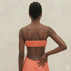 Woman wearing an orange bikini set against a neutral background