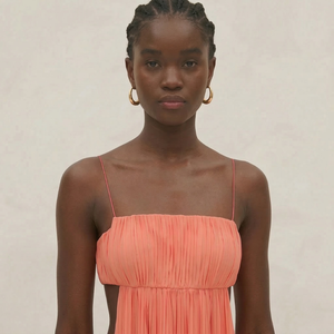 Woman wearing a coral dress against a plain background