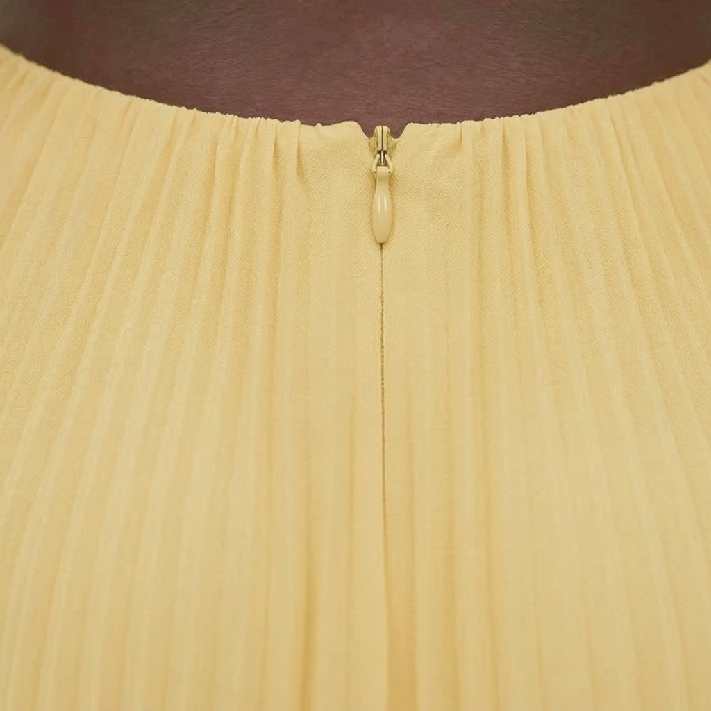 Close-up of a beige skirt with a gold zipper on a dark background