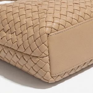 Close-up of a beige woven handbag on a white background