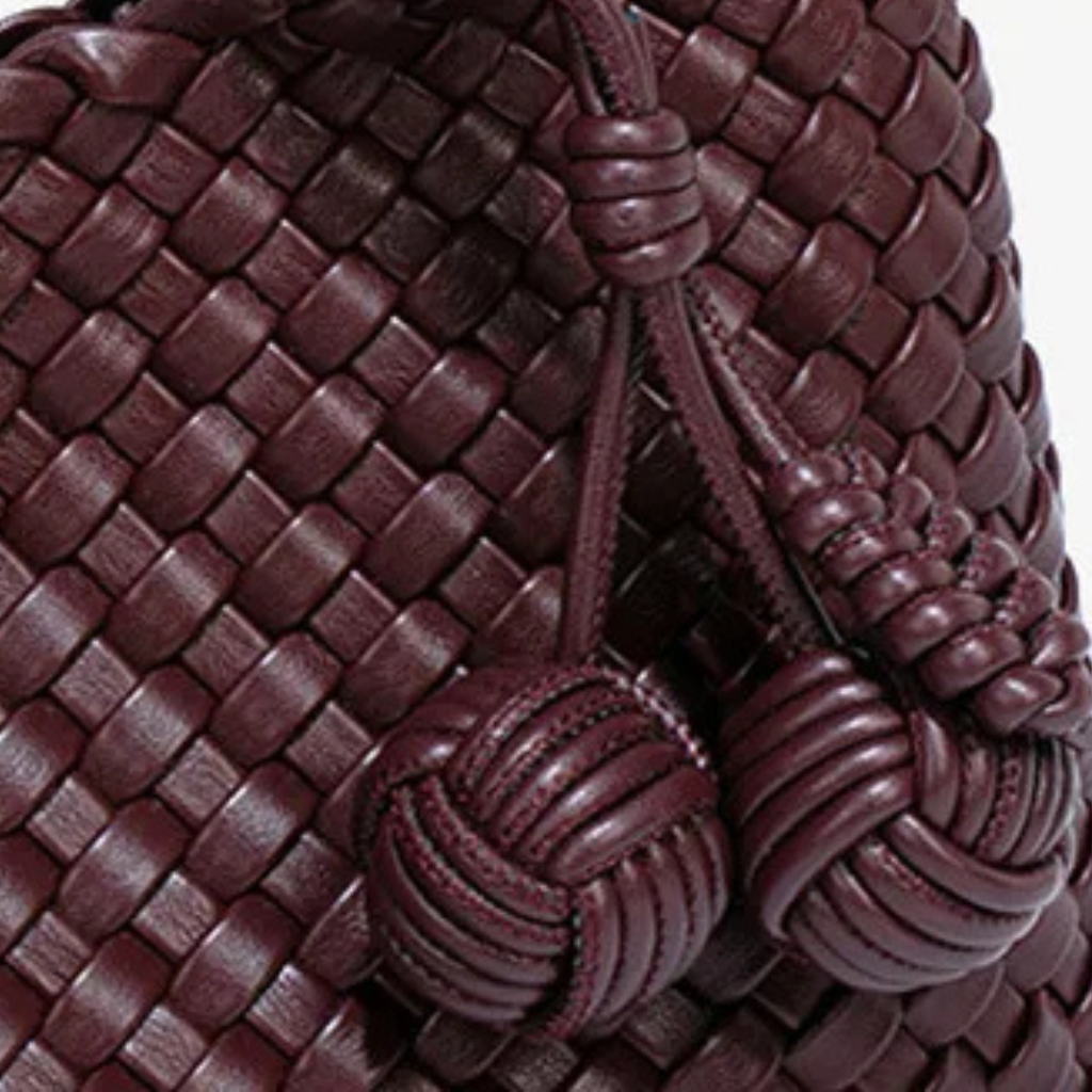 Close-up of a braided brown leather bag with decorative knots.