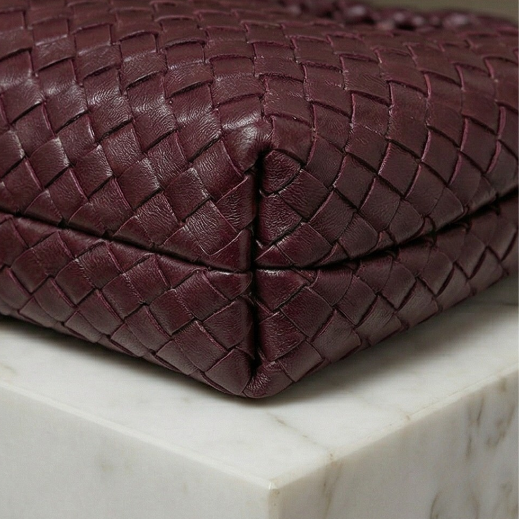 Close-up of a braided brown leather bag on a marble surface