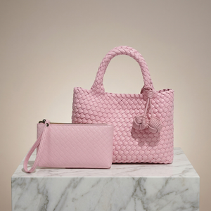 Pink woven handbag and matching pouch on a marble surface with a beige background