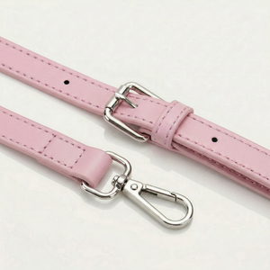 Pink leather belt with silver hardware on a white background