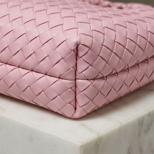 Pink woven handbag on a marble surface