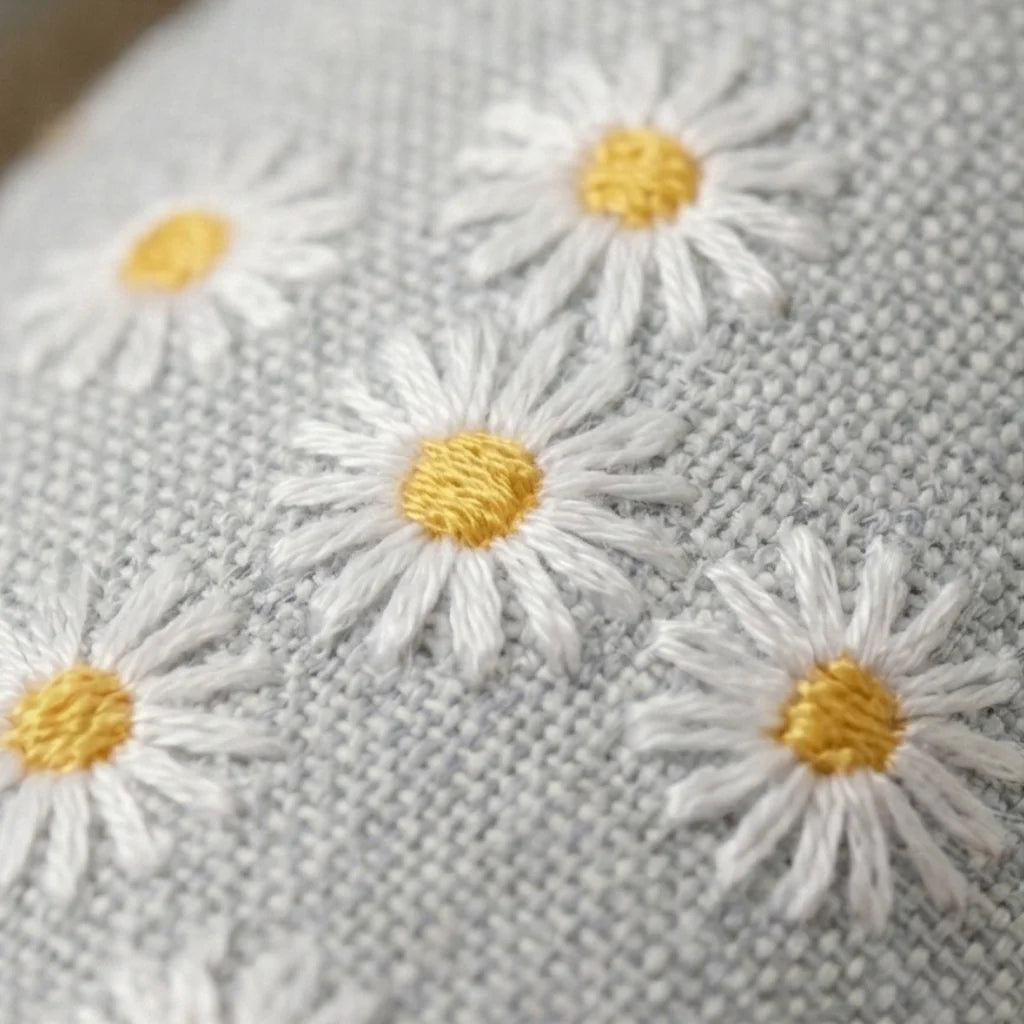 Close-up of embroidered daisies on a fabric background