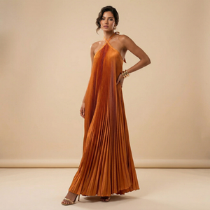 Woman wearing an orange pleated dress against a beige background