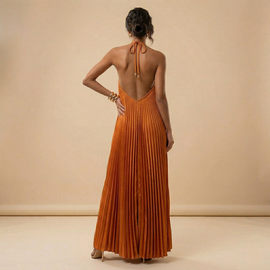 Woman wearing a long orange pleated dress with a beige background