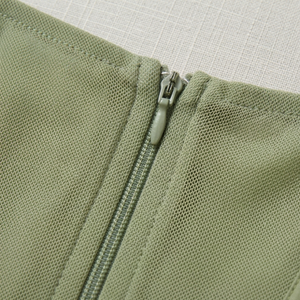 Close-up of a green zipper on a textured fabric background