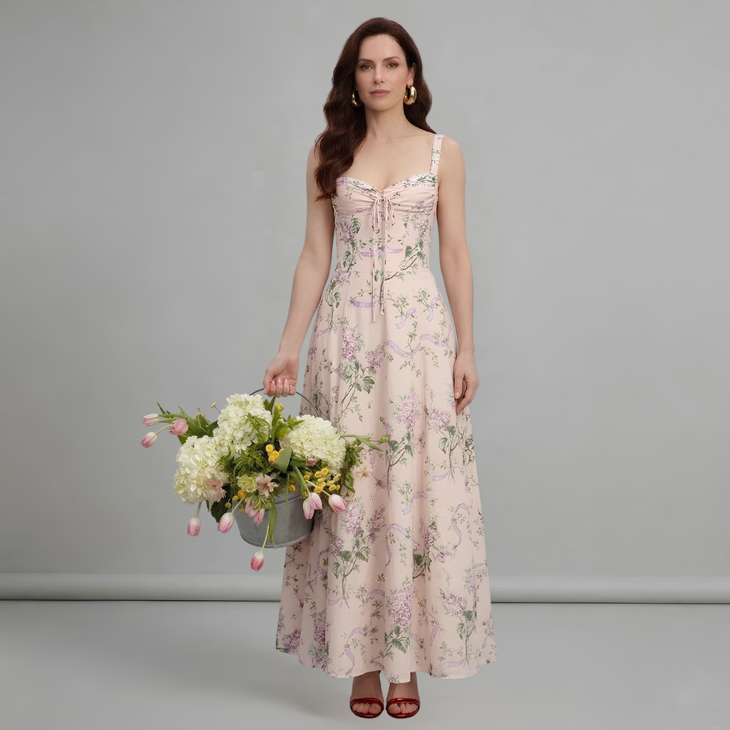 Woman in a floral dress holding flowers against a gray background