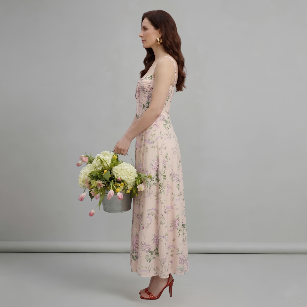 Woman in a floral dress holding a bouquet of flowers against a plain background