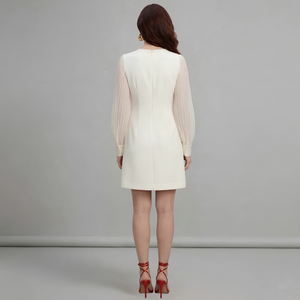 Woman wearing a white dress with sheer sleeves against a gray background