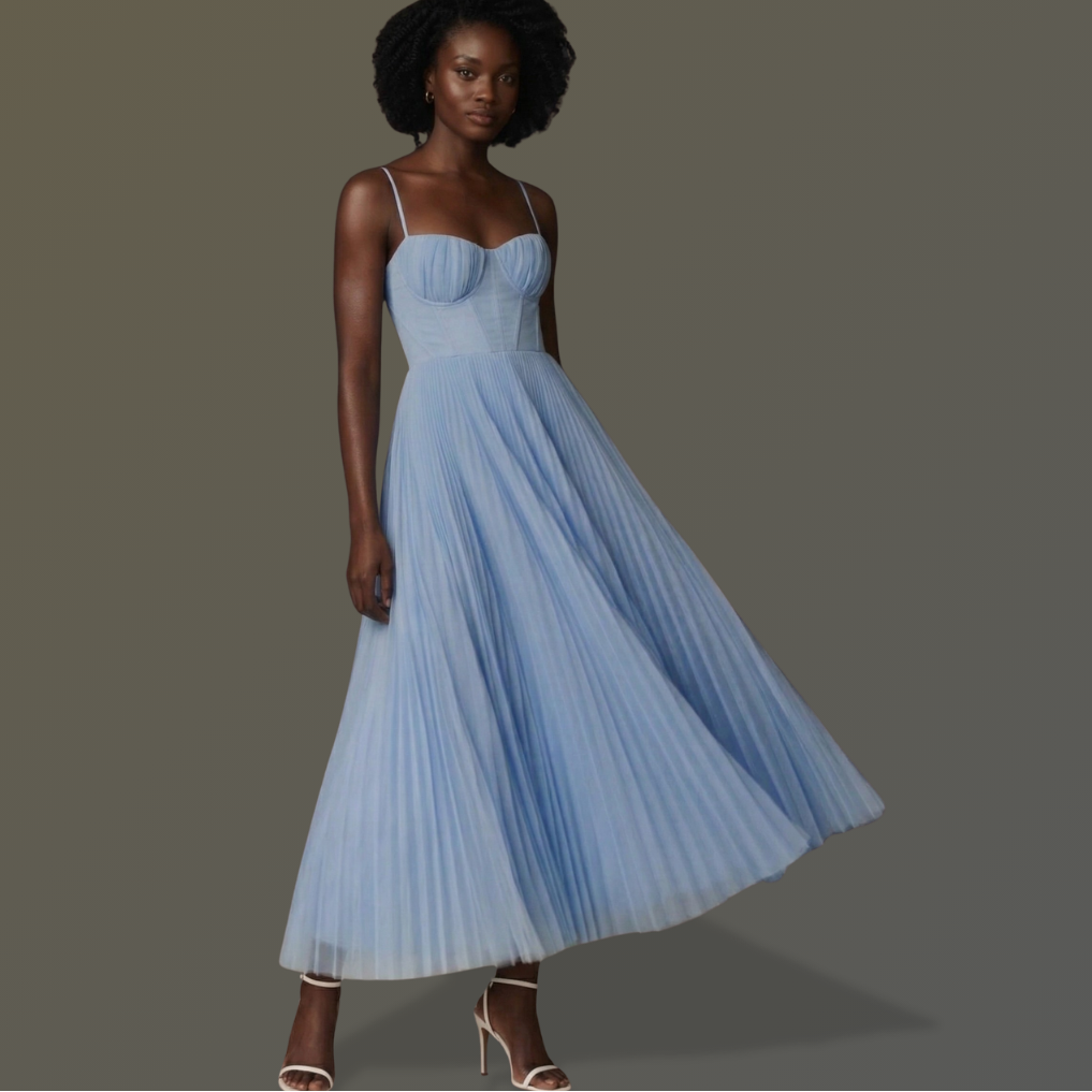 Woman wearing a light blue pleated dress against a gray background