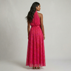 Woman wearing a pink halter neck dress against a plain background