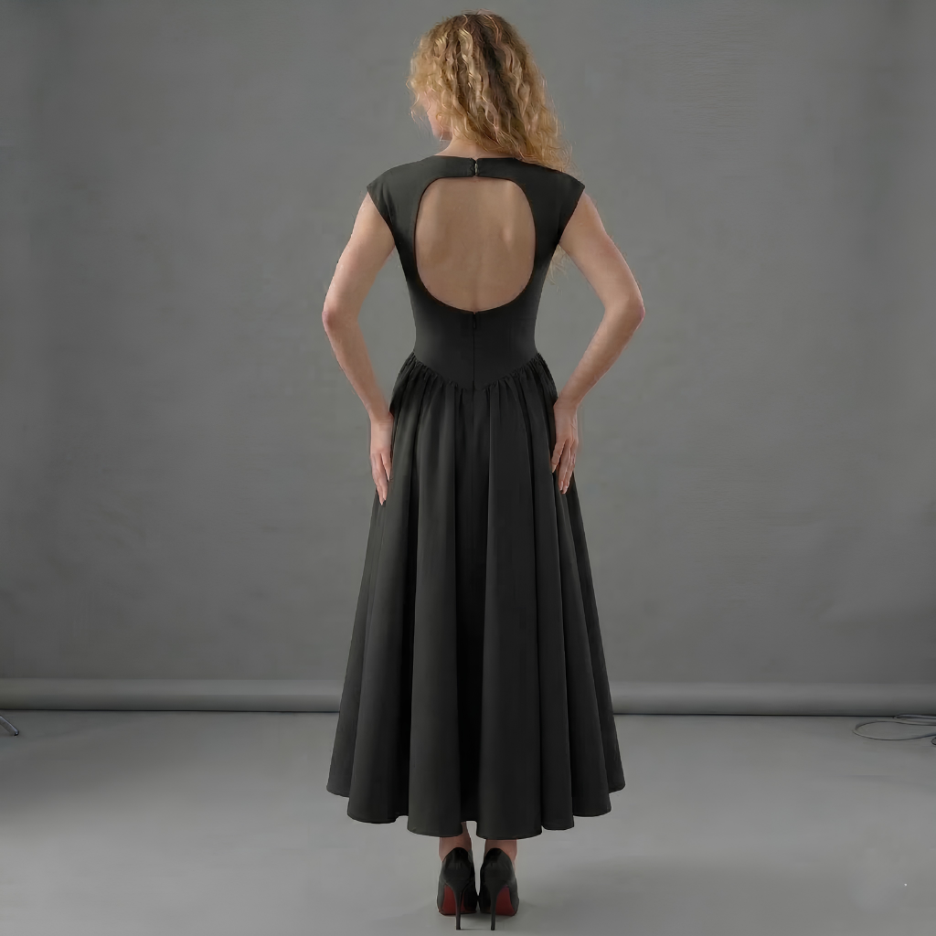 Woman wearing a black dress with an open back against a gray background