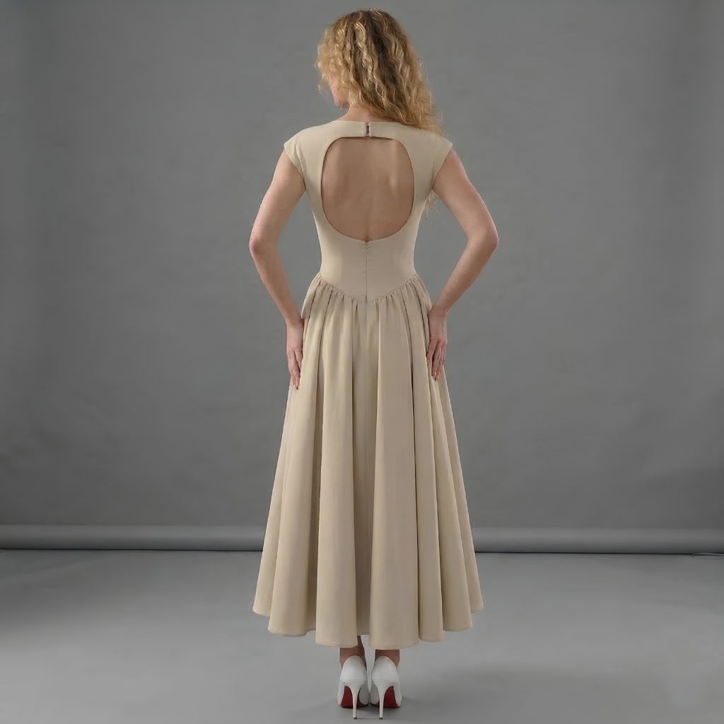 Woman wearing a beige dress with an open back against a gray background