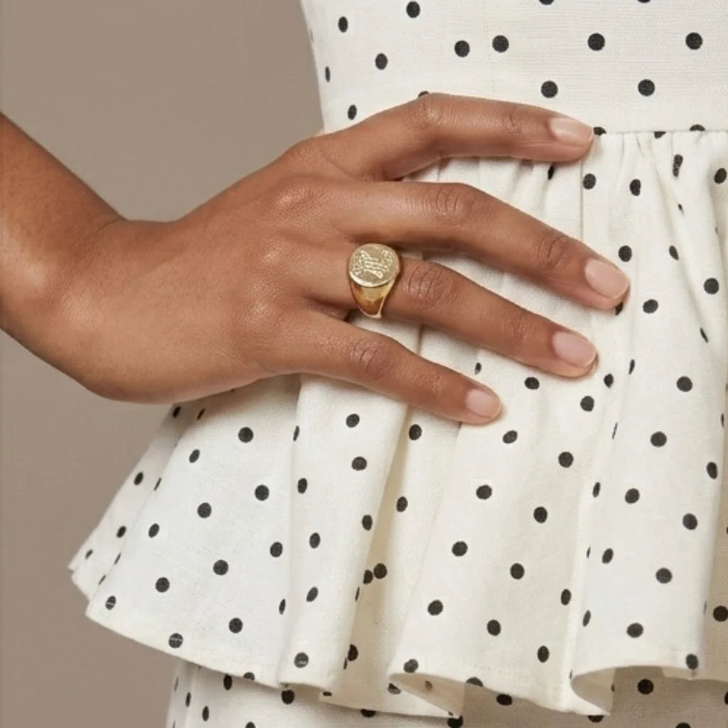 Hand wearing a gold ring on a polka dot dress