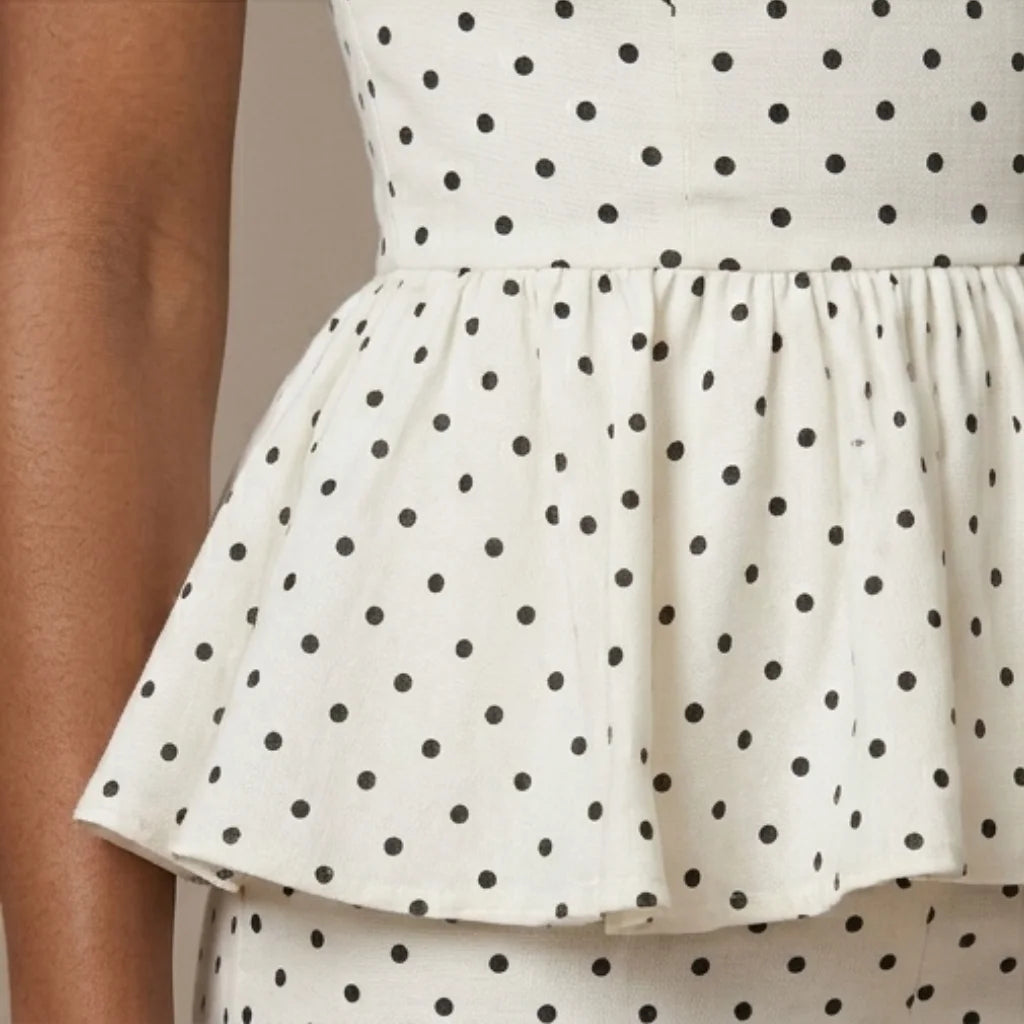 White dress with black polka dots on a neutral background
