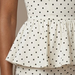 White dress with black polka dots on a neutral background