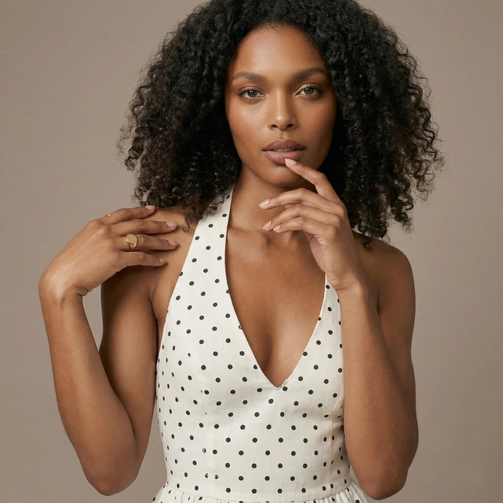 Woman wearing a white polka dot dress against a beige background