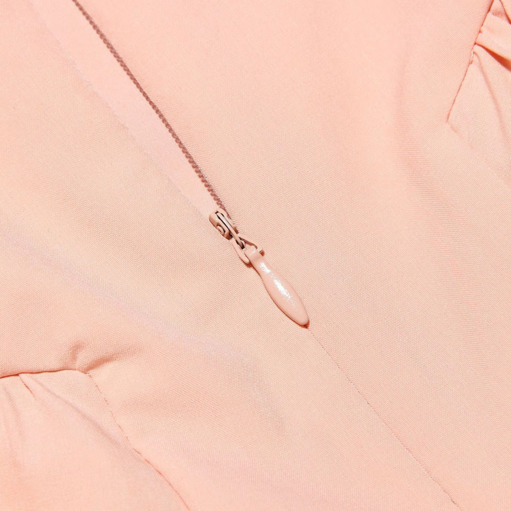 Close-up of a pink zipper on a pink fabric background