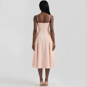 Woman wearing a light pink dress with thin straps on a white background